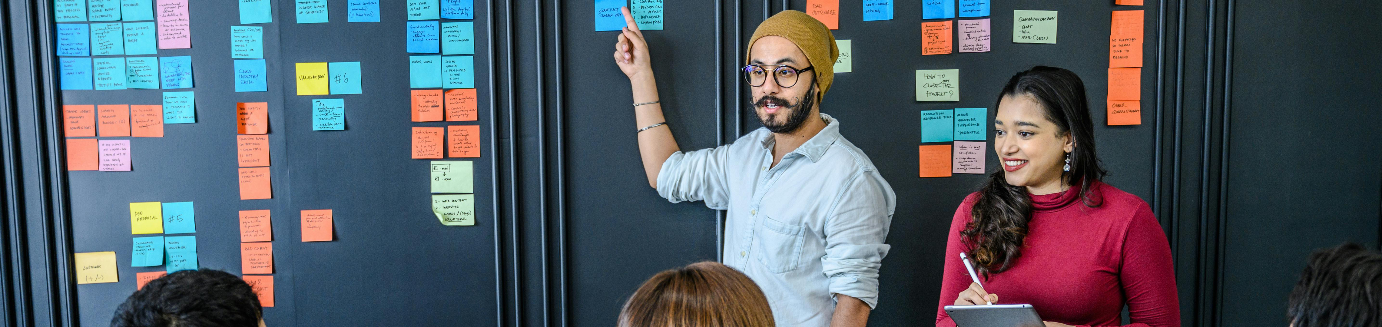 Marketing team discussing go-to-market strategy using board and sticky notes